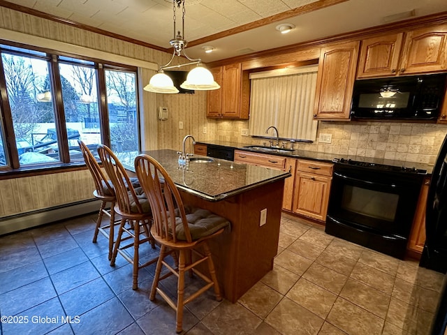 kitchen featuring sink, black appliances, hanging light fixtures, and a center island with sink