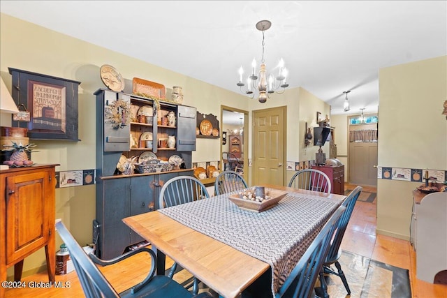 dining space with rail lighting, an inviting chandelier, and light tile patterned flooring