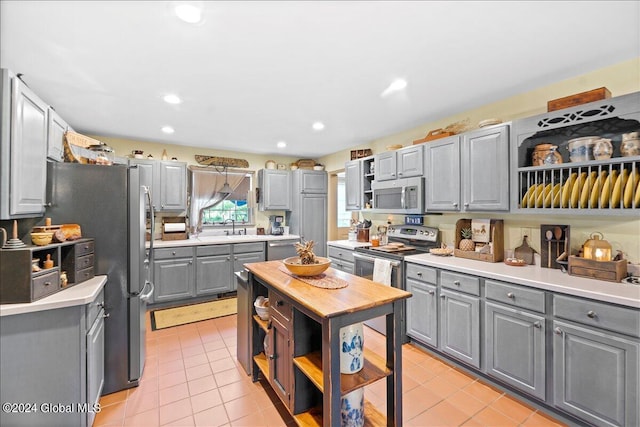 kitchen with gray cabinets, sink, light tile patterned floors, and stainless steel appliances