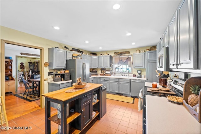 kitchen featuring gray cabinets, light tile patterned floors, sink, and appliances with stainless steel finishes