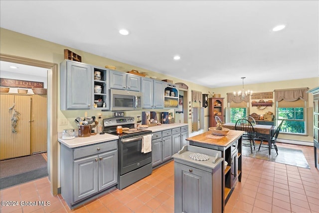 kitchen with appliances with stainless steel finishes, light tile patterned floors, decorative light fixtures, and a kitchen island