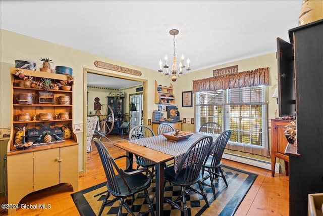 dining space featuring baseboard heating, light hardwood / wood-style floors, and an inviting chandelier