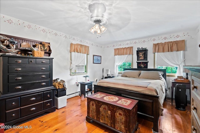 bedroom with baseboard heating, cooling unit, and light hardwood / wood-style floors