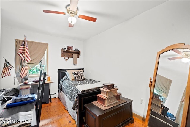 bedroom featuring light wood-type flooring, ceiling fan, and a baseboard heating unit