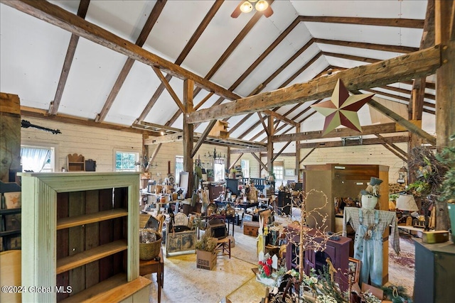 interior space featuring beam ceiling, wood walls, ceiling fan, and high vaulted ceiling