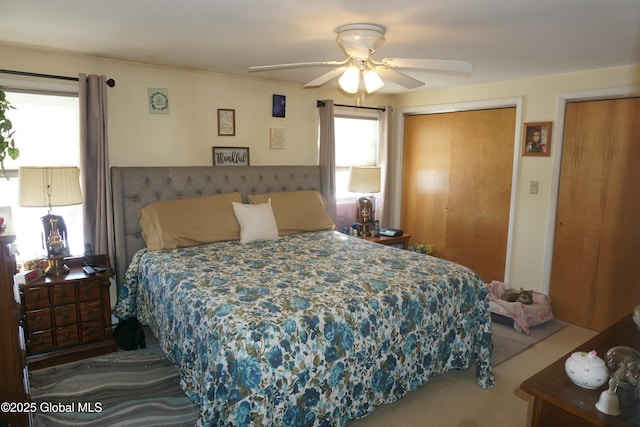 bedroom featuring multiple windows, carpet, multiple closets, and ceiling fan