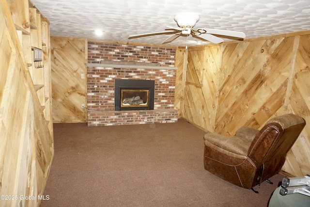 unfurnished living room featuring a fireplace, carpet floors, ceiling fan, and wood walls