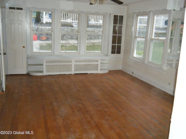 unfurnished sunroom featuring a wealth of natural light, ceiling fan, and radiator