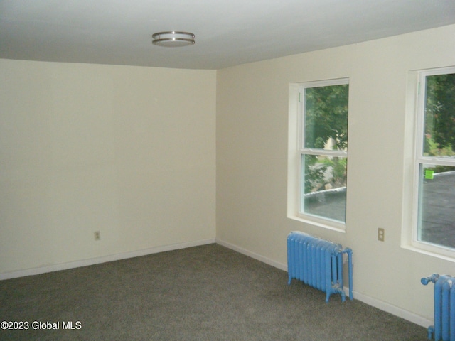 empty room with dark colored carpet and radiator heating unit