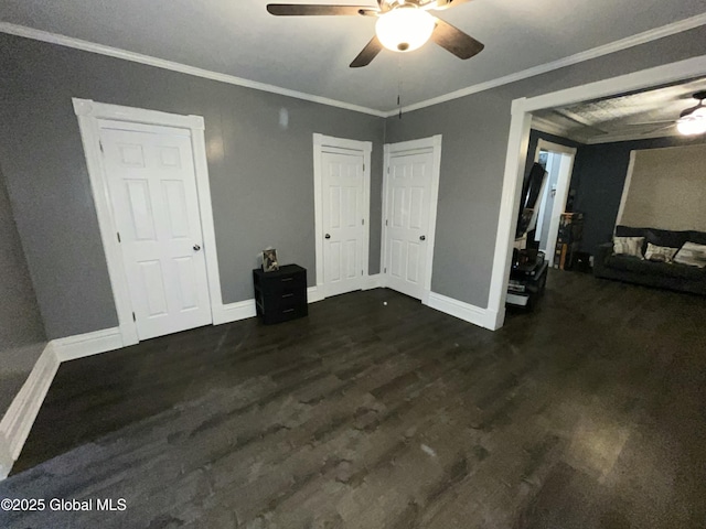 unfurnished bedroom featuring dark hardwood / wood-style flooring, multiple closets, crown molding, and ceiling fan