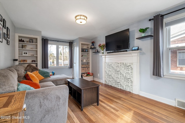 living room featuring built in shelves and light hardwood / wood-style floors