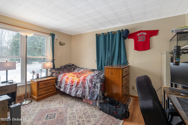 bedroom with multiple windows and light hardwood / wood-style flooring