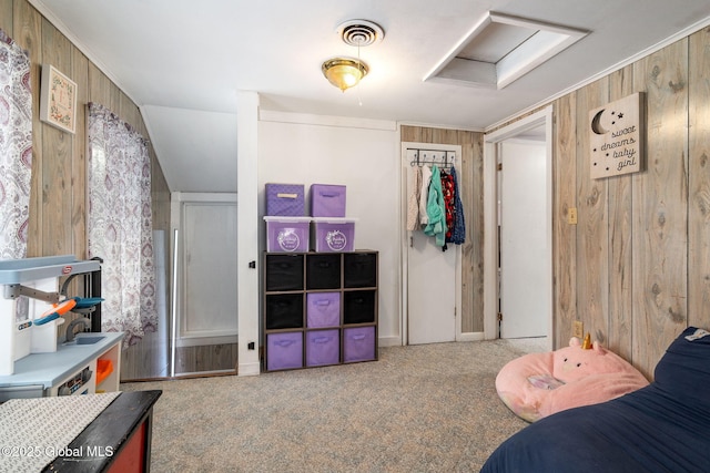 carpeted bedroom with a closet and wood walls