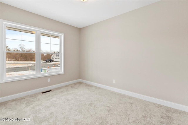 empty room with carpet floors, visible vents, and baseboards