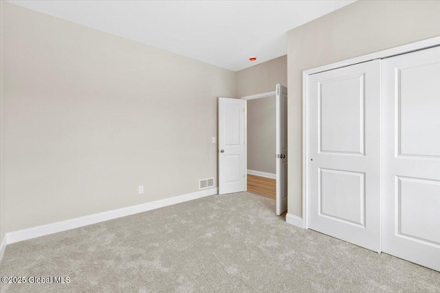 unfurnished bedroom featuring a closet, carpet, visible vents, and baseboards