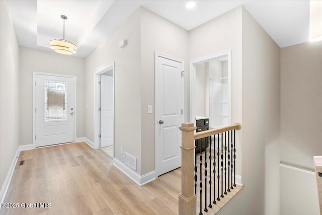 foyer featuring light wood-style floors, visible vents, and baseboards