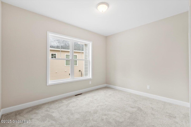 carpeted empty room featuring visible vents and baseboards