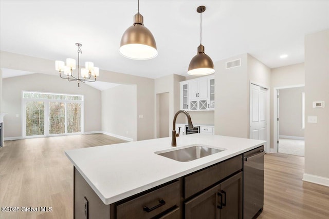 kitchen featuring dark brown cabinetry, a sink, light wood-style floors, light countertops, and dishwasher