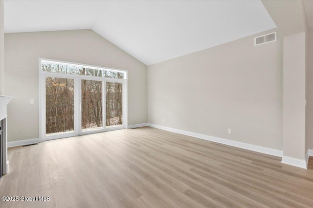 unfurnished living room with lofted ceiling, light wood-type flooring, a fireplace, and visible vents