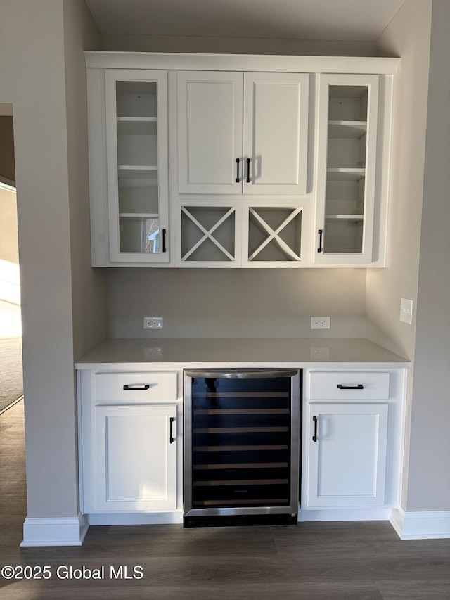 bar with dark wood-style floors, wine cooler, a dry bar, and baseboards