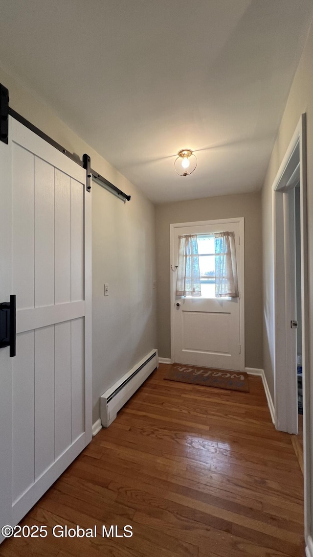 entryway with a barn door, hardwood / wood-style floors, and a baseboard radiator