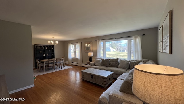 living room featuring dark hardwood / wood-style floors, a baseboard radiator, a wealth of natural light, and an inviting chandelier