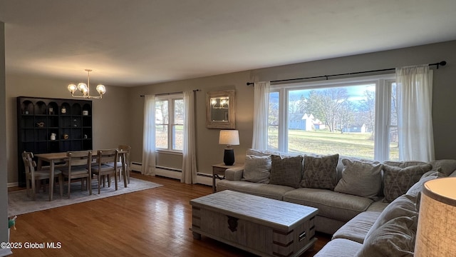 living room with wood-type flooring, a baseboard heating unit, and a notable chandelier