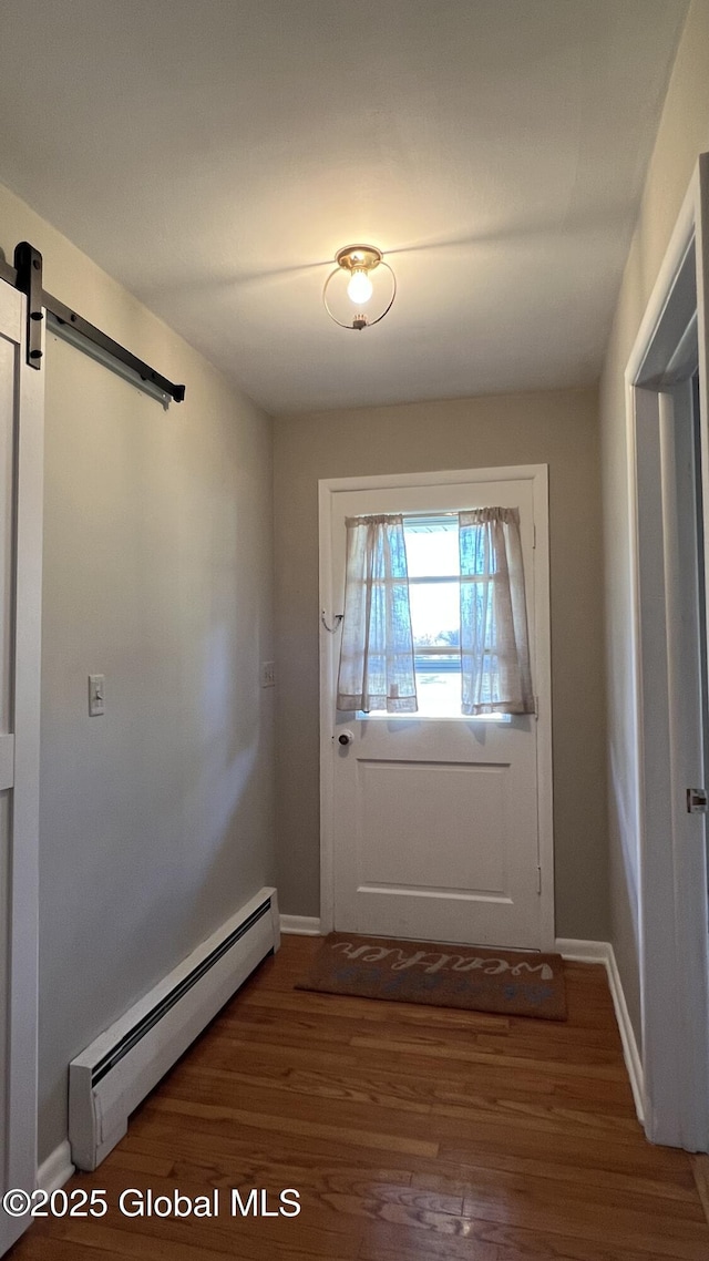 doorway with a barn door, dark hardwood / wood-style floors, and a baseboard heating unit