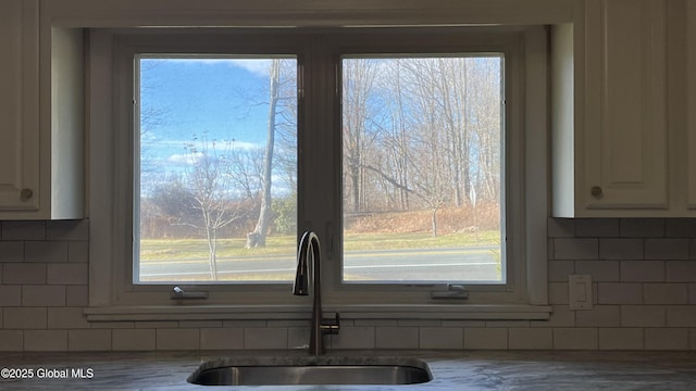 room details with decorative backsplash, sink, and white cabinets