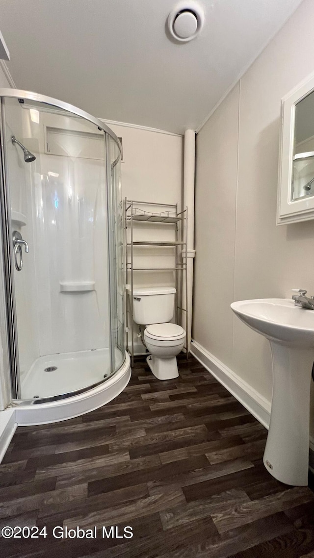 bathroom featuring sink, hardwood / wood-style floors, a shower with shower door, and toilet