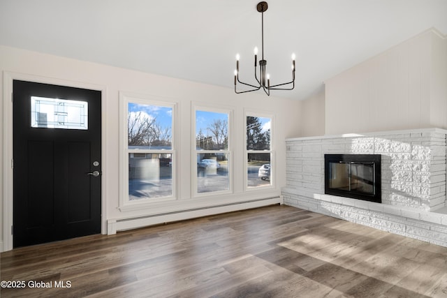 unfurnished living room featuring a baseboard radiator, an inviting chandelier, a stone fireplace, hardwood / wood-style floors, and lofted ceiling