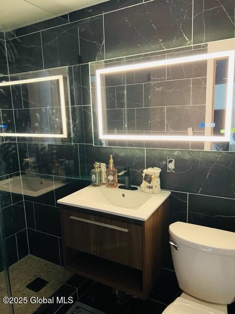 bathroom featuring tile patterned floors, vanity, tile walls, and toilet