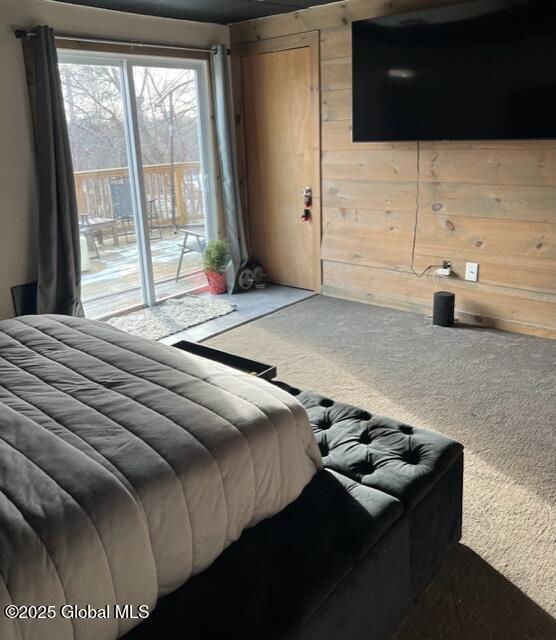 carpeted bedroom with access to outside and wooden walls