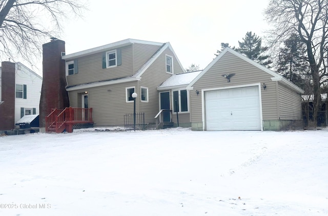 snow covered back of property featuring a garage