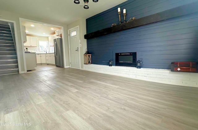 unfurnished living room featuring a fireplace, light hardwood / wood-style floors, and sink