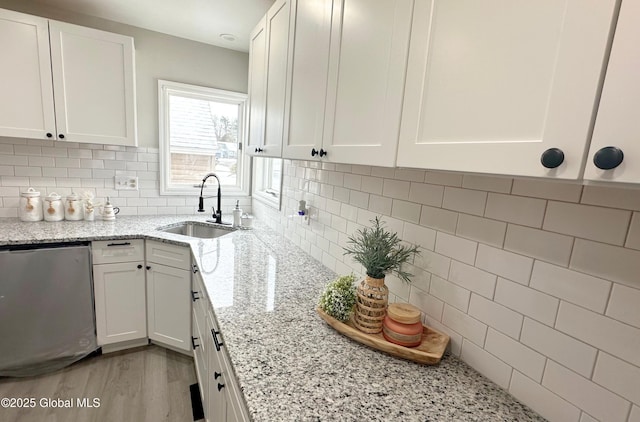 kitchen with backsplash, white cabinetry, sink, and light stone countertops