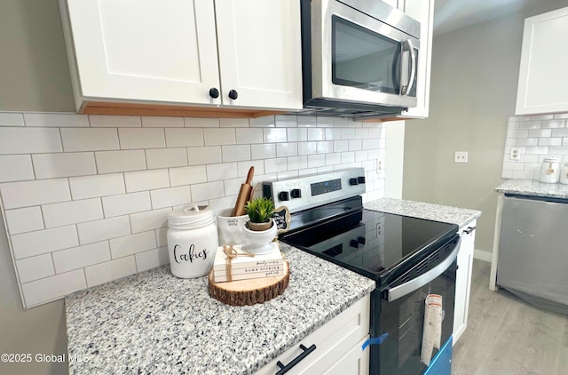 kitchen featuring decorative backsplash, light stone counters, stainless steel appliances, white cabinets, and light hardwood / wood-style floors