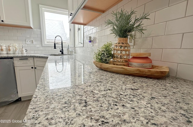 kitchen with white cabinets, light stone countertops, and sink