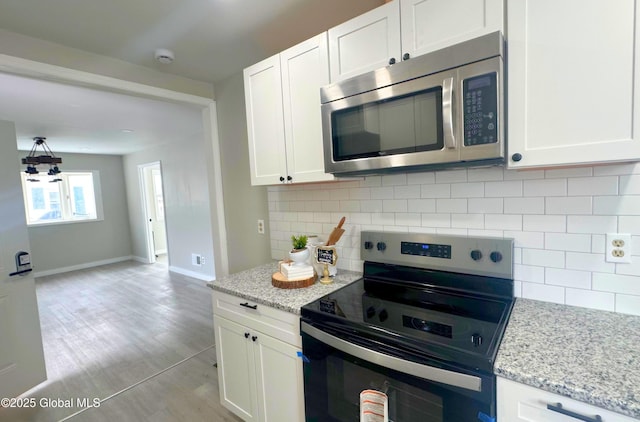 kitchen with white cabinetry, light stone counters, backsplash, light tile patterned floors, and appliances with stainless steel finishes