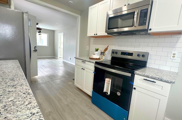 kitchen featuring tasteful backsplash, white cabinetry, light stone counters, and appliances with stainless steel finishes