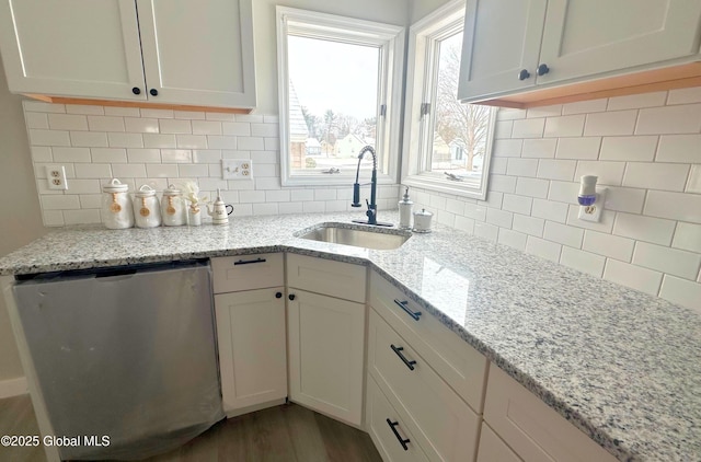 kitchen featuring light stone counters, sink, white cabinets, and stainless steel dishwasher