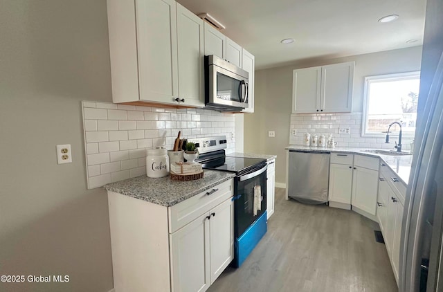 kitchen with light stone countertops, sink, white cabinetry, and stainless steel appliances