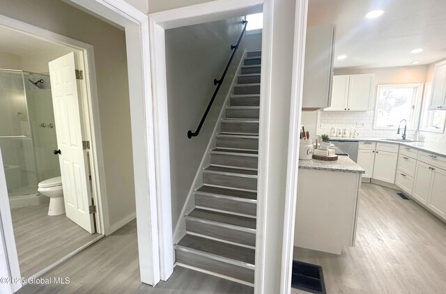 stairs featuring wood-type flooring and sink