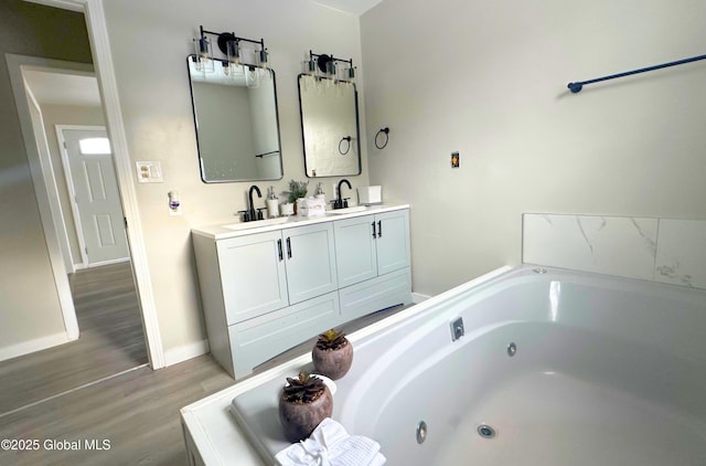 bathroom with a washtub, wood-type flooring, and vanity