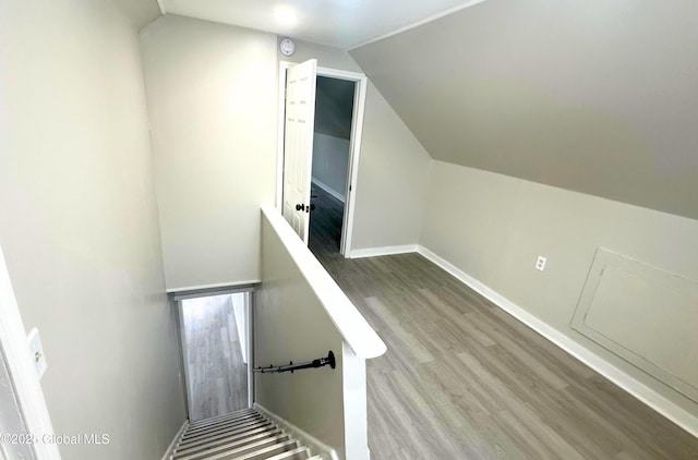 stairway with wood-type flooring and lofted ceiling