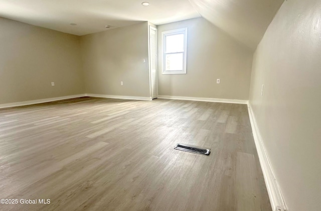 additional living space with light hardwood / wood-style floors and vaulted ceiling