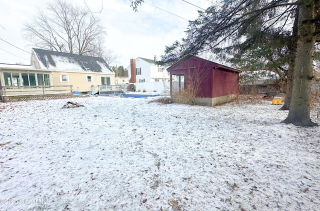 yard covered in snow featuring an outbuilding and a wooden deck