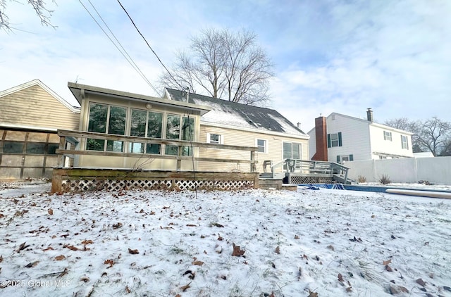 snow covered property with a sunroom and a deck