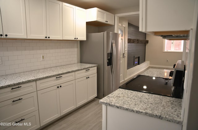 kitchen with stainless steel fridge with ice dispenser, white cabinetry, stove, and light stone counters