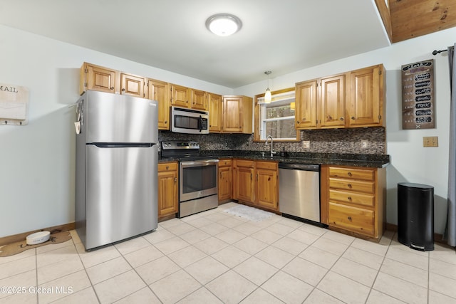 kitchen with decorative light fixtures, stainless steel appliances, backsplash, and sink